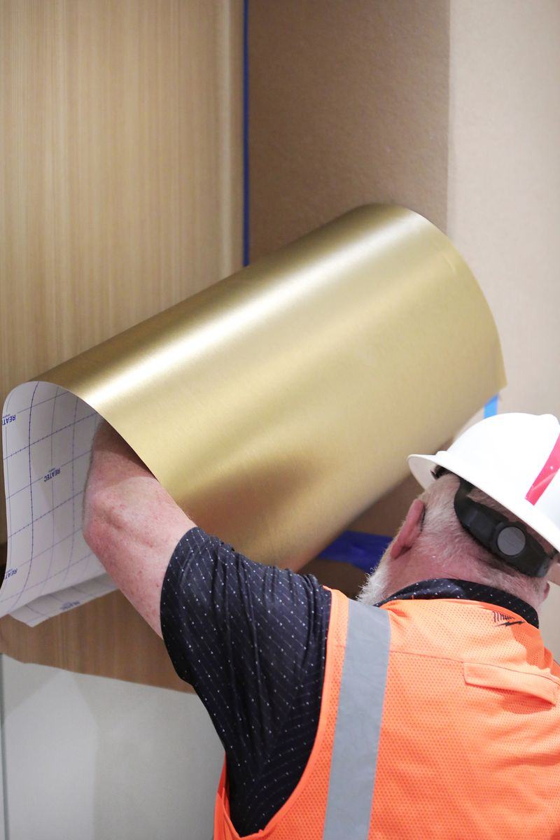 Installer unrolling gold metallic architectural film